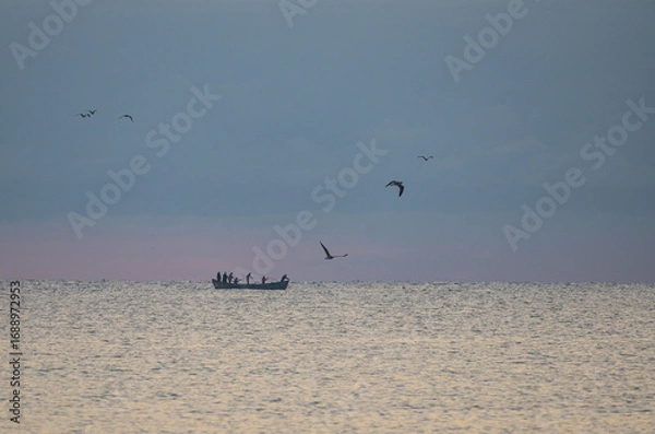 Fototapeta Seascape. Fishermen in boats pull nets with fish from the sea in the early hours of the morning.