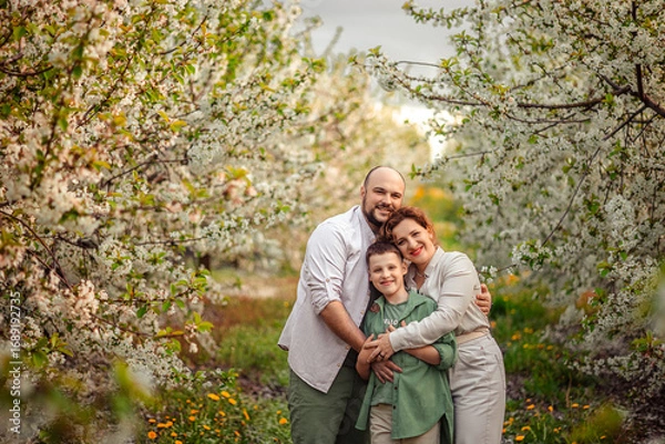 Fototapeta Happy family mom dad and teenager boy having fun on a spring walk in a blooming park