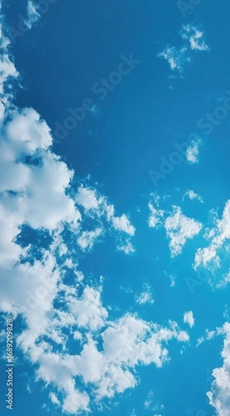 Obraz A clear blue sky speckled with scattered, fluffy white clouds on a bright day. High-angle, natural lighting