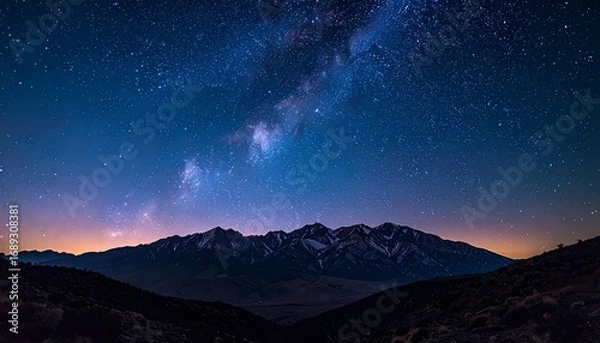 Fototapeta Starry night sky with the Milky Way stretching above snow-capped mountain peaks, creating a serene and breathtaking twilight landscape.