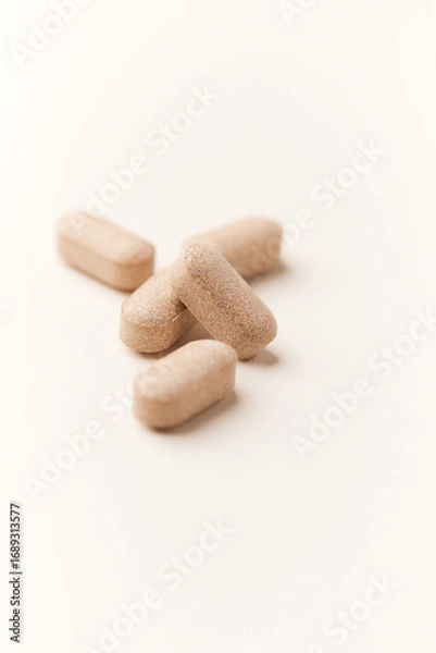 Fototapeta Lion’s mane mushrooms tablets that have beneficial effects on the body, especially the brain, heart, and intestines. Bright paper background. Soft focus. Close up. Copy space.	