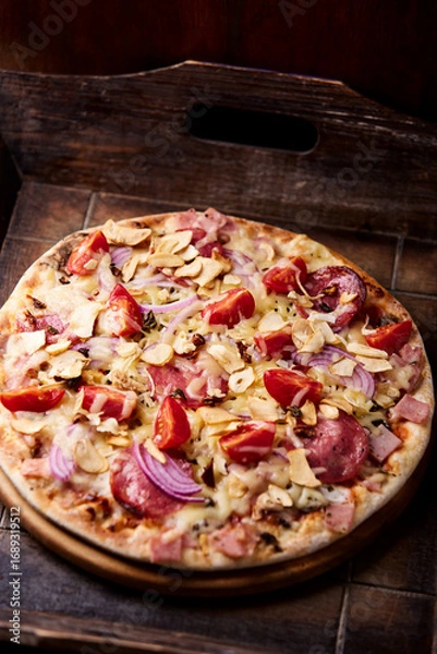 Fototapeta Pizza with ham, salami, cherry tomatoes and mozzarella cheese. Rustic wooden background. Soft focus. 	
