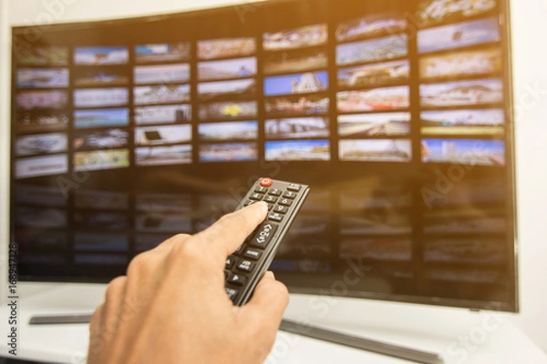 Fototapeta Hand pressing remote of smart tv
