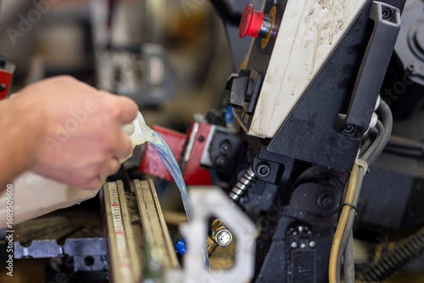 Fototapeta Adding coolant to a large hacksaw for metal and wood. Industrial machine maintenance