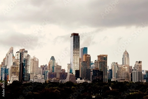 Fototapeta A modern city with towering skyscrapers under a dramatic cloudy skyThe sepia tone effect creates an urban and artistic atmosphere perfect for business architecture and cityscape themes Here in Bangkok