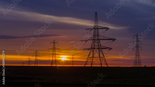 Fototapeta Electricity Pylons at Sunrise Across a Remote Countryside Landscape