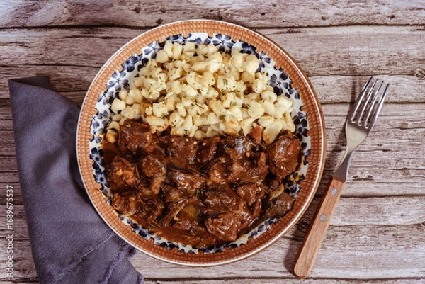 Fototapeta Delicious hungarian goulash with spaetzle served on a rustic wooden table