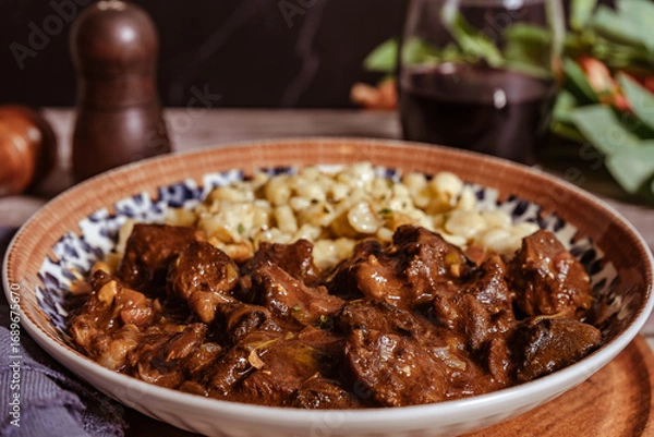 Fototapeta Delicious hungarian goulash with spaetzle and red wine being served on a plate