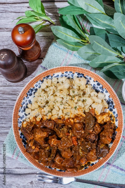 Fototapeta Delicious hungarian goulash with spaetzle on rustic wooden table
