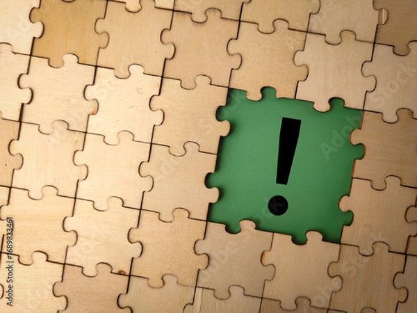 Fototapeta The image displays a jigsaw puzzle with a central piece featuring an exclamation mark on a green background