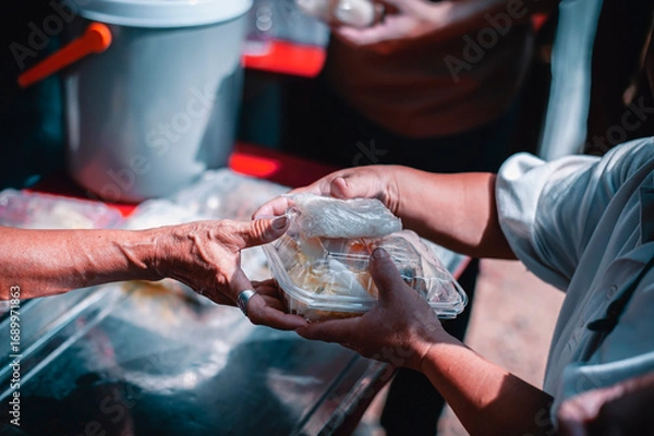 Fototapeta Feeding the poor to hands of a beggar Poverty concept Charity concept, hands of the poor receive food from the donor's share