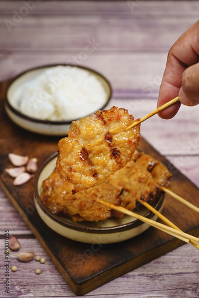 Fototapeta Moo ping grilled pork skewers with sticky rice on a restaurant table