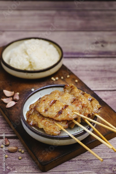Fototapeta Moo ping grilled pork skewers with sticky rice on a restaurant table