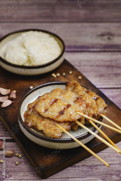 Fototapeta Moo ping grilled pork skewers with sticky rice on a restaurant table