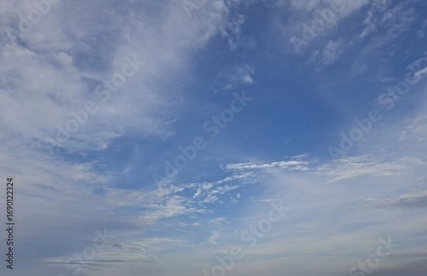 Fototapeta A serene view of a bright blue sky with soft white clouds scattered across, creating a peaceful and natural atmosphere. Perfect background for concepts of freedom, tranquility, weather