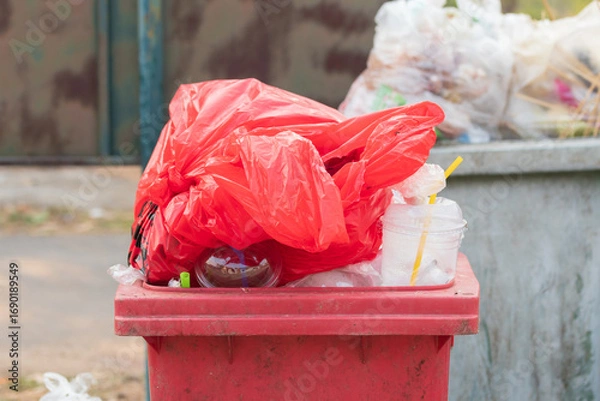 Fototapeta Garbage bins and containers full, overflowing, with bags falling on ground in residential area of Bordeaux, France, in a green container.
