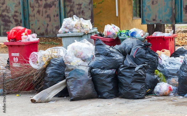 Fototapeta Garbage bins and containers full, overflowing, with bags falling on ground in residential area of Bordeaux, France, in a green container.