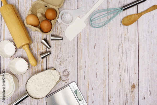 Fototapeta Homemade Dough Recipe (Eggs, flour, milk, sugar) and wooden kneading dough on a wooden table, view from above	
