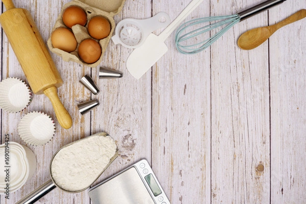 Fototapeta Homemade Dough Recipe (Eggs, flour, milk, sugar) and wooden kneading dough on a wooden table, view from above	
