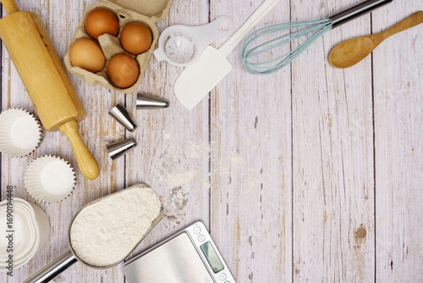 Fototapeta Homemade Dough Recipe (Eggs, flour, milk, sugar) and wooden kneading dough on a wooden table, view from above	
