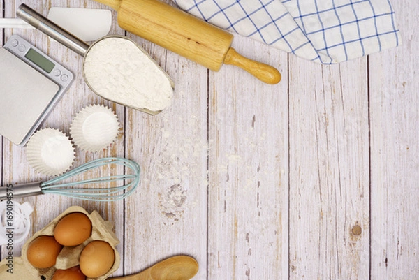 Fototapeta Homemade Dough Recipe (Eggs, flour, milk, sugar) and wooden kneading dough on a wooden table, view from above	
