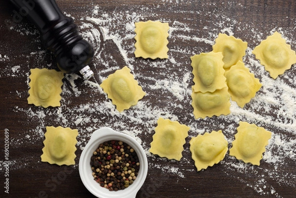 Fototapeta Fresh stuffed ravioli big size on wooden table with flour and eggs