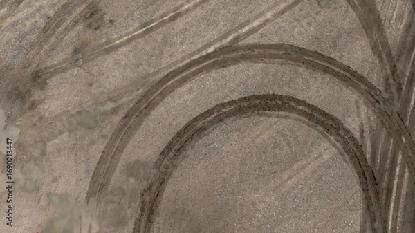 Fototapeta Aerial top view tire track on dirt sand mud, Texture of wet mud road with puddle and Tyre or tire track in countryside, Wheel tyre or tire track on mud, texture and background.