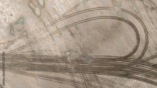Fototapeta Aerial top view tire track on dirt sand mud, Texture of wet mud road with puddle and Tyre or tire track in countryside, Wheel tyre or tire track on mud, texture and background.