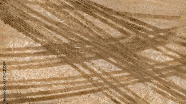 Fototapeta Aerial top view tire track on dirt sand mud, Texture of wet mud road with puddle and Tyre or tire track in countryside, Wheel tyre or tire track on mud, texture and background.