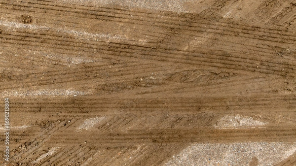 Fototapeta Aerial top view tire track on dirt sand mud, Texture of wet mud road with puddle and Tyre or tire track in countryside, Wheel tyre or tire track on mud, texture and background.