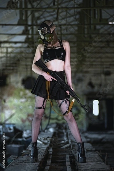 Obraz Beautiful, young girl post apocalypse girl stand in abandoned factory with gas mask and machine gun