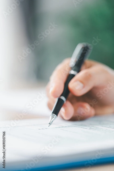 Fototapeta Concept of business planning and financial analysis. A businesswoman writes notes on documents with charts and reports, using laptop and calculator for budget management at modern office desk.