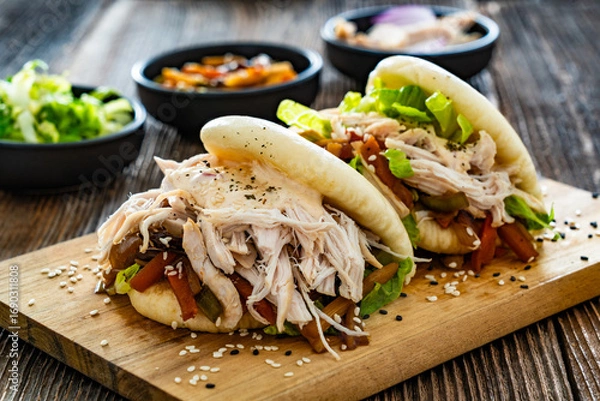 Fototapeta Bao Buns with pulled chicken and vegetables on wooden table	