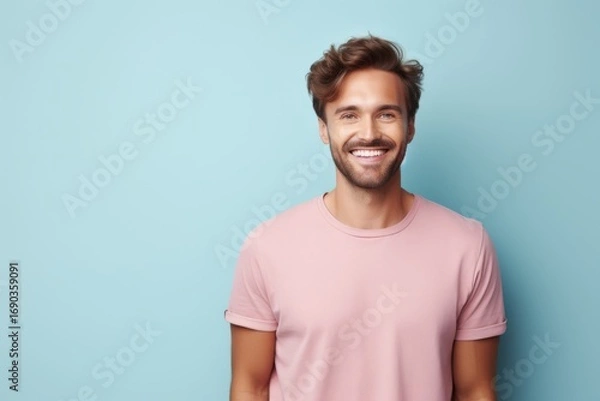Fototapeta Smiling young man with stylish hair standing against a light blue background, exuding confidence and warmth