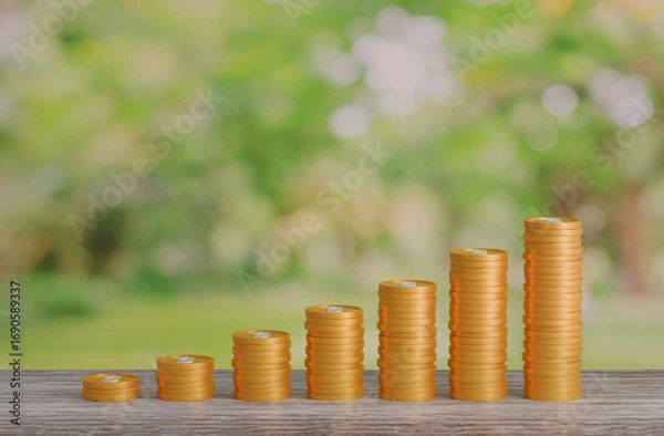 Fototapeta gold coin stacking 3D render on wodden board with photo of green blur nature background for business concept financial, banking and investment with money growth success.