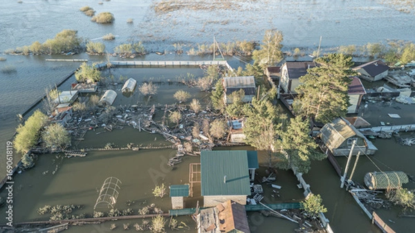 Fototapeta Aerial drone footage showing severe flooding with submerged houses and roads. Wide overhead view of a disaster zone after heavy rainfall, showcasing water damage, extreme weather, and climate-related 