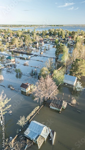 Fototapeta Aerial drone footage showing severe flooding with submerged houses and roads. Wide overhead view of a disaster zone after heavy rainfall, showcasing water damage, extreme weather, and climate-related 