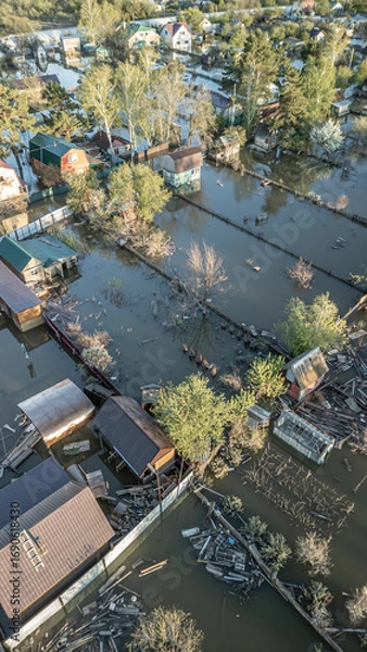 Fototapeta Aerial drone footage showing severe flooding with submerged houses and roads. Wide overhead view of a disaster zone after heavy rainfall, showcasing water damage, extreme weather, and climate-related 