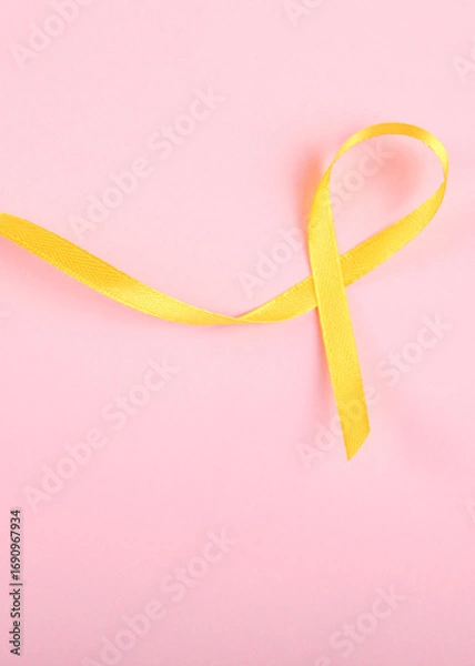 Fototapeta yellow ribbon symbolizing cancer in children top view. Vertical photo format