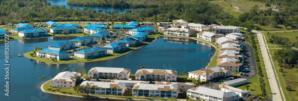 Fototapeta Residential condos with leaking roofs covered with protective tarp sheets against rain water leaks until replacement of shingles. Damage of building rooftops as aftermath of hurricane in Florida