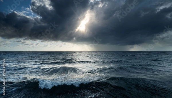 Fototapeta Rainy Day Scene With Dark Clouds And A Bright Sun Shining Over The Ocean Waves