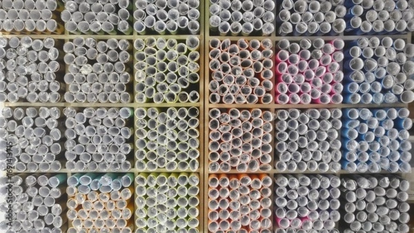 Fototapeta Top view of colorful paper rolls neatly arranged on store shelves in a stationery shop, showcasing vibrant textures and organized display for school, craft, or office supplies