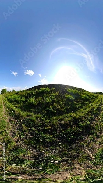 Fototapeta Panoramic view of a grassy hill under a bright sky