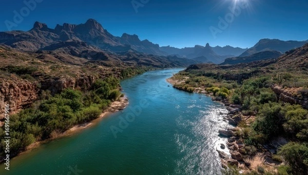 Fototapeta Sunny river winds through arid mountains