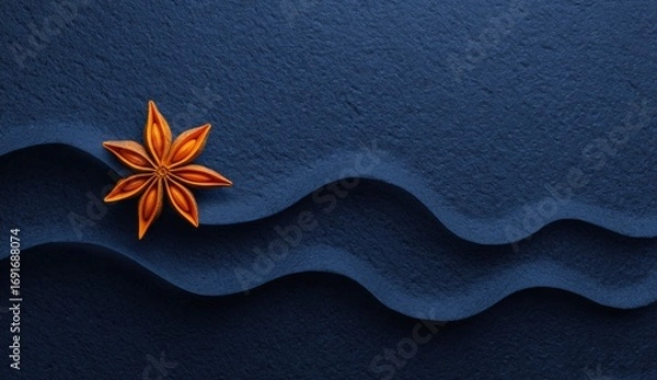 Fototapeta A single star anise rests on a dark blue surface with sculpted waves