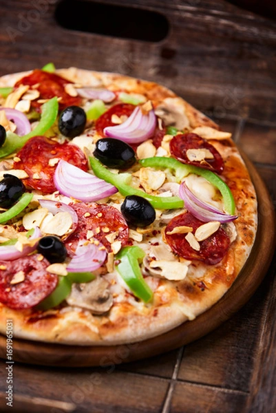 Fototapeta Pizza with chorizo ​​sausage, mozzarella cheese, green pepper and black olives. Rustic wooden background. Soft focus.