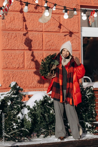 Fototapeta A woman walks along a city street on Christmas Eve in search of gifts and a good mood