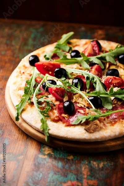 Fototapeta  Pizza with salami, tomatoes and mozzarella cheese, black olives and arugula. Rustic wooden background. Soft focus. 