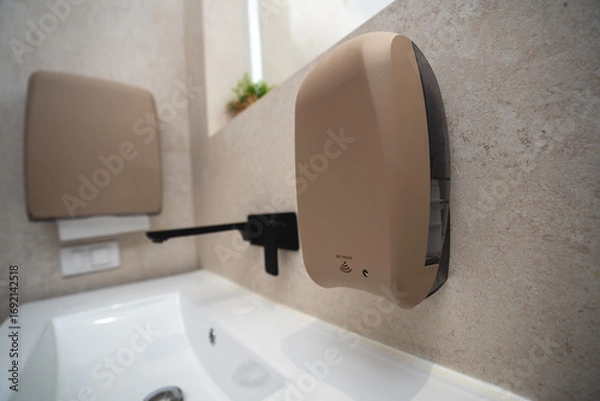 Fototapeta Sandy texture touchless soap dispenser in a luxury bathroom