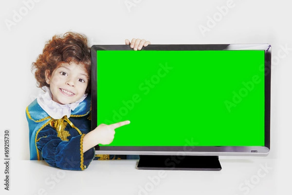 Fototapeta Cute curly red-haired prince points his index finger on a green screen set. Close-up. Gray background.